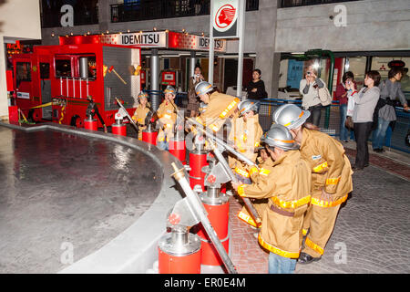 Kidzania in Nishinomiya, Japan. Interior. A row of children dressed as firemen manning hoses awaiting the command to turn them on while parents watch. Stock Photo