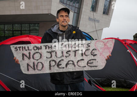 Homeless people in Liverpool, Merseyside, UK 24th May, 2015. Mr Christopher Gandy   The Love Activists for the homeless, who occupied the Bank of England building on Castle Street till evicted, have now erected tents at the Pier Head. Several new tents have been pitched, creating an eyesore, on a green patch in between the Cunard Building and the ferry terminal, with placards on display protesting issues such as homelessness, austerity and tax evasion. One sign prominently displayed at the front of the site said 'Still on the streets. No justice, no peace.' Stock Photo