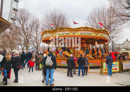 LONDON - APRIL 4: Carousel at the Thames riverbank crowded with tourists on April 4, 2015 in London, UK. Stock Photo