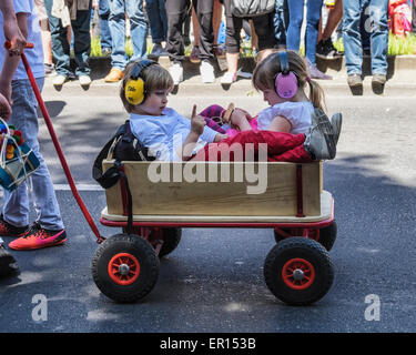 Kreuzberg, Berlin, Germany, 24th May 2015. Two young children with earmuffs in wood wagon in the parade as Berlin celebrates its cultural diversity at  the Carnival of Cultures at Pentecost  every year. The  Grand finale is the street parade on Pentecost Sunday where thousands of dancers, musicians and artists perform and about a million people from all over the world watch. Stock Photo