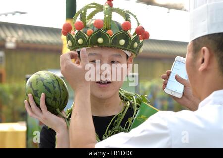Beijing, China. 25th May, 2015. A chef puts his watermelon carving on a man's head during the 27th Daxing Watermelon Festival in Panggezhuang Township of Daxing District of Beijing, capital of China, May 25, 2015. Credit:  Gao Jianjun/Xinhua/Alamy Live News Stock Photo