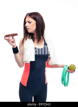 Sporty woman making choice between apple and chocolate isolated on a white background Stock Photo
