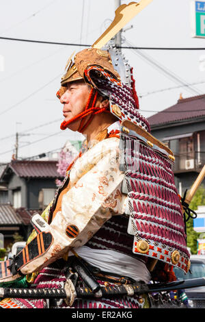 Japanese man dressed in full samurai armour and Kabuto helmet, on horseback riding through city street in the Genji parade at Tada in Japan. Stock Photo