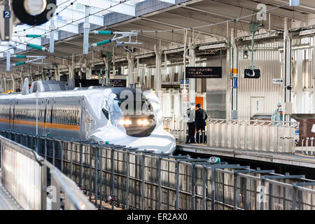 Shin Osaka station in Japan. A 700 series Shinkansen, bullet train, in the livery of the 'Rail Star;' arriving at a platform with its headlights on. Stock Photo