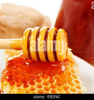 closeup of a honeycomb and a honey dipper with honey, and some honey jars in the background Stock Photo