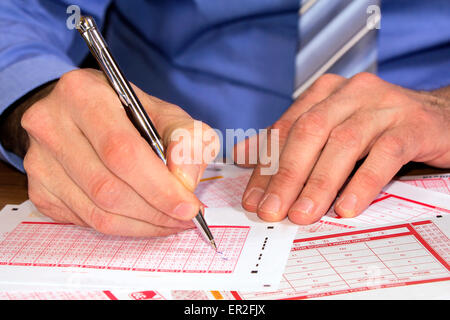 Man Marking on lottery ticket with a pen Stock Photo