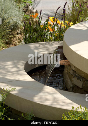 A close-up of a tiered stone fountain in The Royal Bank of Canada Garden designed by Mathew Wilson at The Chelsea Flower Show Stock Photo