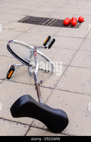 A unicycle and juggling balls lie on a footpath Stock Photo