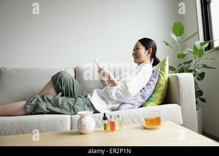 Woman using a Smartphone on the sofa Stock Photo