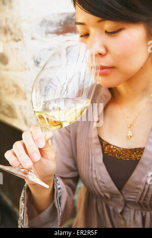 Young Japanese woman tasting wine in a fashionable bar Stock Photo