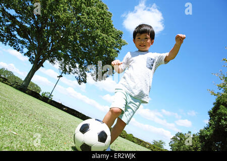 Japanese young boy playing soccer in a city park Stock Photo