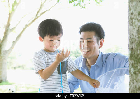 Happy Japanese father and son catching insects in a city park Stock Photo