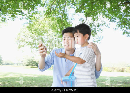 Happy Japanese father and son catching insects in a city park Stock Photo
