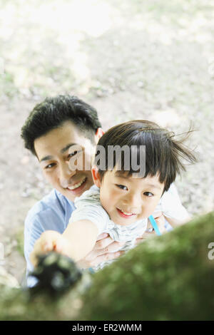 Happy Japanese father and son catching insects in a city park Stock Photo