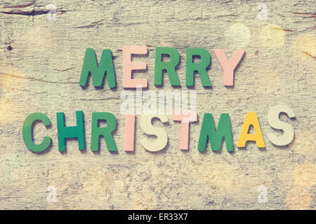 The colorful words 'MERRY CHRISTMAS' made with wooden letters on old wooden board. Stock Photo