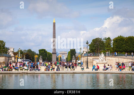 Paris, France - August 09, 2014: Pond in Jardin des Tuileries with walking tourists, view on Avenue des Champs-Elysees and Place Stock Photo
