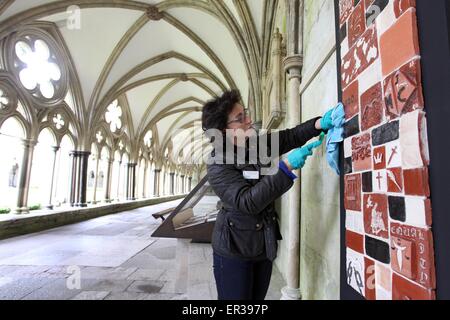 Salisbury, UK. 26th May, 2015. Prison Art exploring the Magna Carta from the perspective of offenders installed in the Salisbury Cathedral Cloisters. 26th May 2015 Picture Dominic Parkes. Jacquiline Creswell, Salisbury Cathedral Curator and Visual Arts Advisor, adds the finishing touches to a montage of tiles on display in Salisbury Cathedral Cloisters opening on Tuesday 26th May. Created by offenders from nearby Erlestoke prison as part of a series of workshops entitled Alternative Perspective, the montage explores Magna Carta from the perspective of offenders. Stock Photo