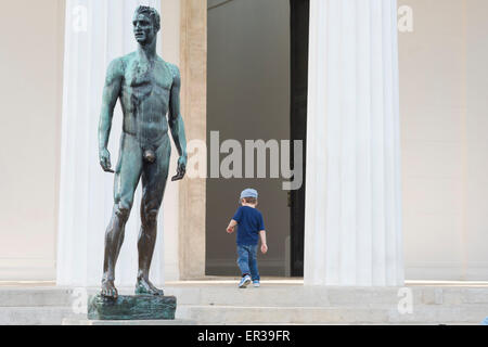 Man and boy, view of a child walking past a sculpture of an athletic man outside the Temple of Theseus in the Volksgarten in Vienna, Wien, Austria. Stock Photo