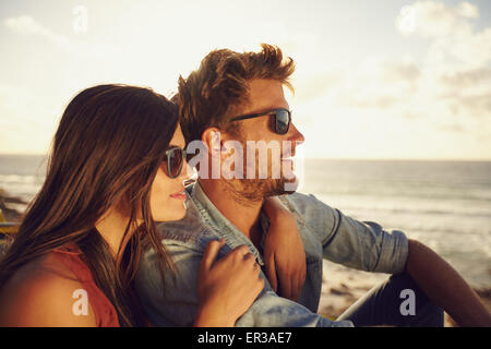 Beautiful young couple together outdoors on a summer day. Caucasian couple enjoying the beach view, both wearing sunglasses. Stock Photo
