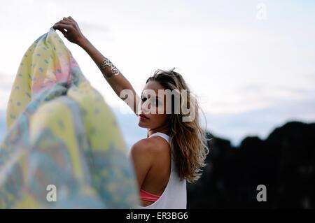 Beautiful woman standing on a beach holding a sarong Stock Photo
