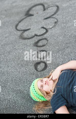 Girl lying on ground with thought bubbles Stock Photo