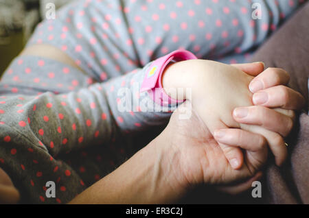 Mother and daughter sitting together and holding hands Stock Photo