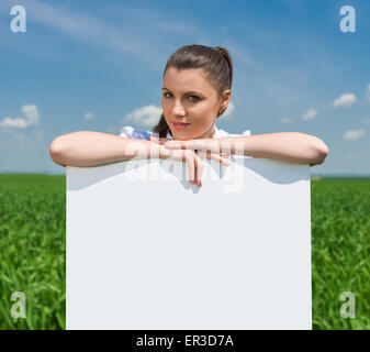 girl with blank billboard on green field Stock Photo