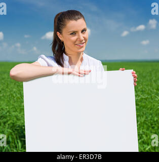 girl with blank billboard on green field Stock Photo