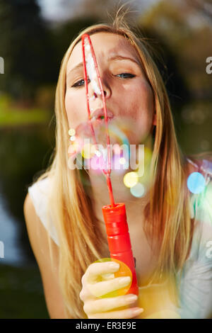 Young woman blowing clorful soap bubbles in summer Stock Photo