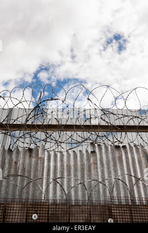 Galvanised high security razor wire and barbed wires deterrent to slow down climbing over walls with mass of corrugated spikes Stock Photo