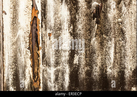 painted outer skin of corrugated metal sheet beginning to fail and rust with interesting patterns from diesel fumes Stock Photo