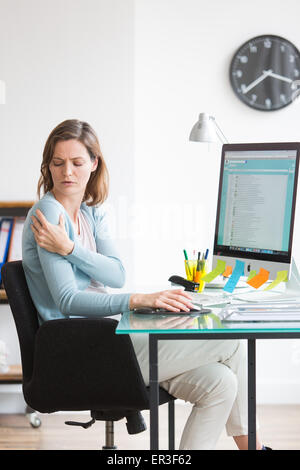 Woman at work suffering from shoulder pain. Stock Photo