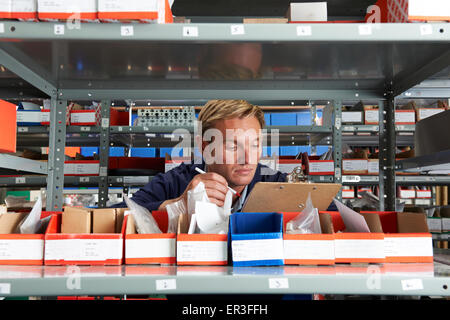 Factory Worker In Store Room Checking Stock Stock Photo