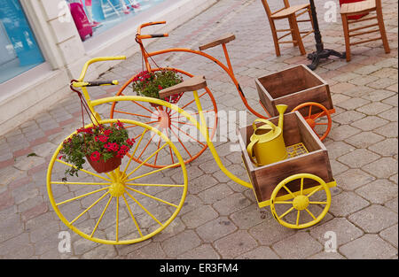 Ornamental penny farthing tricycles planters, with trugs on display in Fethiye's old town, Turkey. Stock Photo