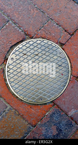 Manhole Cover on a Brick Road Stock Photo