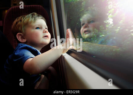 Baby boy gazing out train window in awe Stock Photo