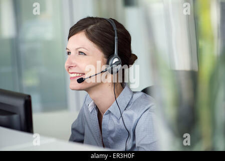 Receptionist wearing headset, smiling cheerfully Stock Photo