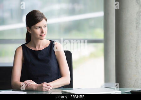 Business executive at desk looking away contemplatively Stock Photo