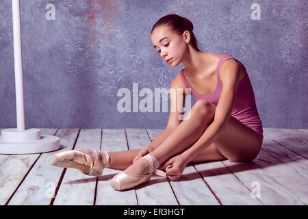 young ballerina putting on her ballet shoes.