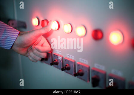 Worker pressing illuminated buttons on industrial control panel Stock Photo