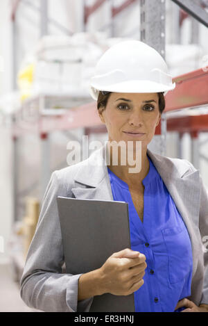 Businesswoman with hard hat in warehouse, portrait Stock Photo