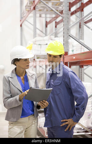 Female manager speaking with warehouse worker Stock Photo