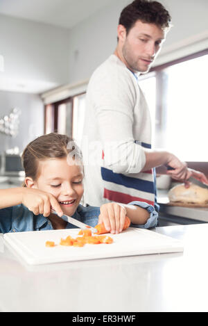 Little girl helping her father prepare food in kitchen Stock Photo