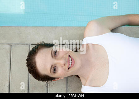 Young woman sunbathing by pool, smiling cheerfully, portrait Stock Photo
