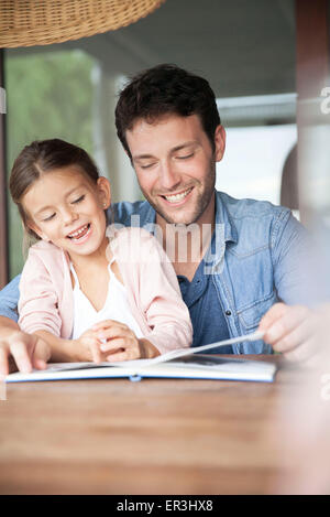 Father and daughter reading book together Stock Photo