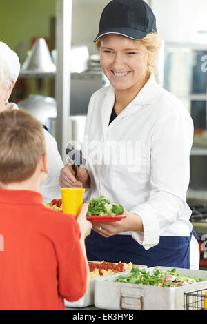 Pupil In School Cafeteria Being Served Lunch By Dinner Lady Stock Photo