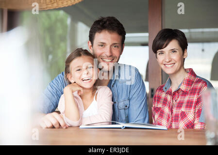 Family sitting together at table with open book, portrait Stock Photo