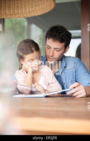 Father and young daughter reading together Stock Photo