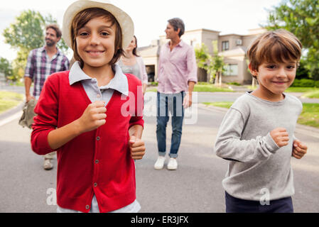 Boys running outdoors, family in background Stock Photo