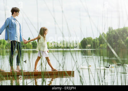 Mother and daughter holding hands on dock Stock Photo